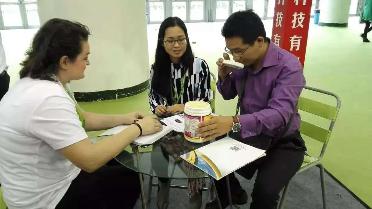 Interpreting at a Xiamen trade exhibition while an overseas buyer samples a supplier's product